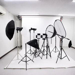 Photography studio setup with a white seamless backdrop and multiple studio lights, softboxes, and stands arranged for shooting the scene.