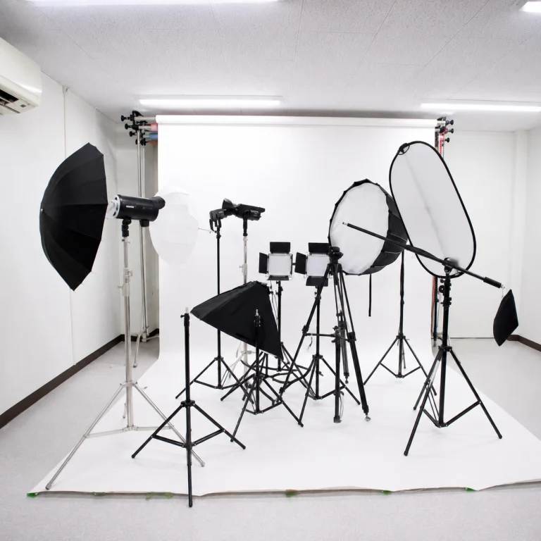 Photography studio setup with a white seamless backdrop and multiple studio lights, softboxes, and stands arranged for shooting the scene.